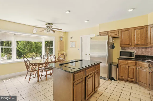 a kitchen with stainless steel appliances granite countertop a table chairs and a refrigerator