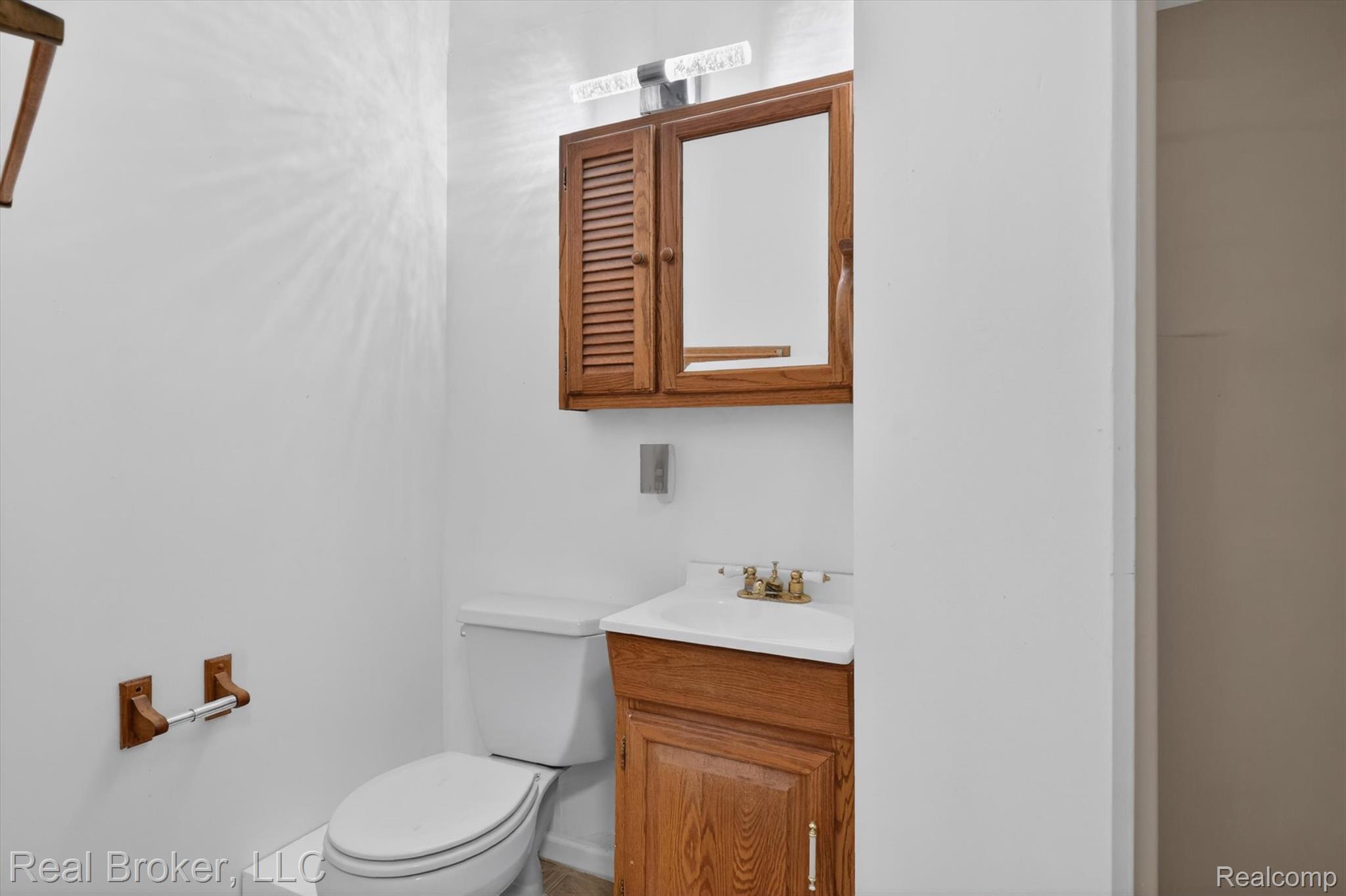 48050 Hull Road Belleville, MI 48111 - Photo 25 of 39 Bathroom vanity with wood-finish cabinetry, a built-in sink, and a mirrored medicine cabinet