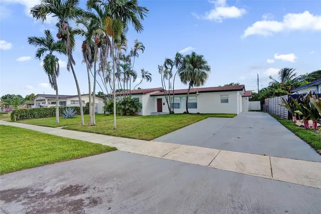 a view of a house with a yard and palm trees