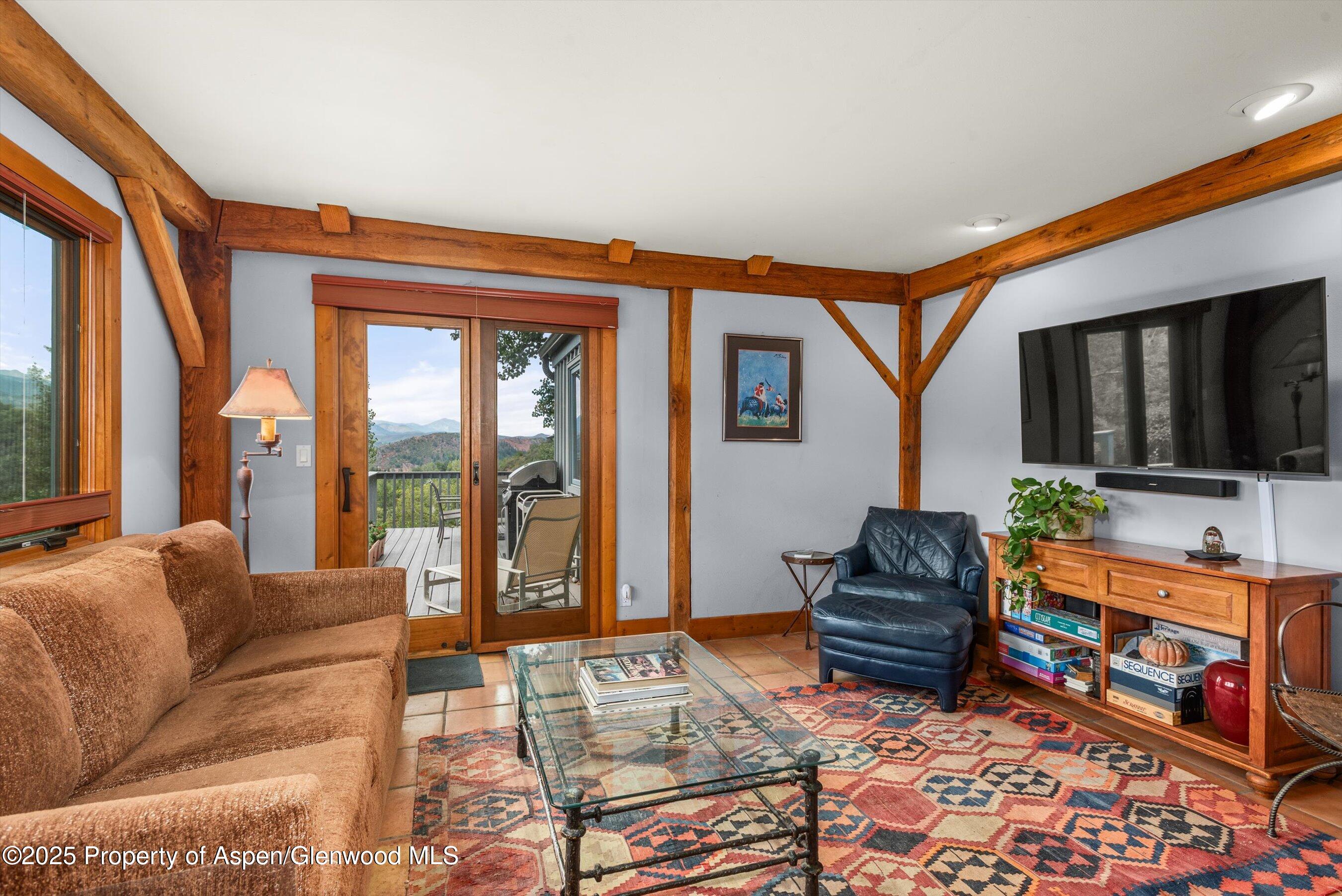 927 Red Mountain Road Aspen, CO 81612 - Photo 11 of 37 a living room with furniture a flat screen tv and a floor to ceiling window