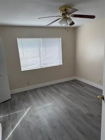 en empty room with wooden floor chandelier fan and windows