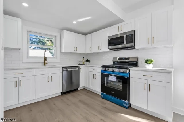 a kitchen with white cabinets stainless steel appliances and window