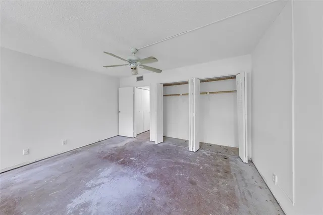 an empty room with a ceiling fan and a window