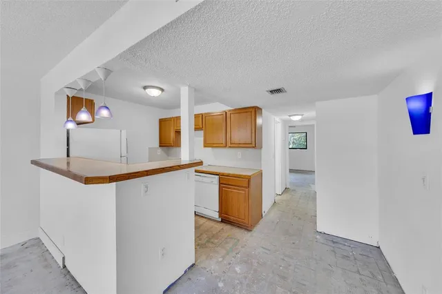 a large white kitchen with granite countertop a sink and dishwasher a stove with wooden floor