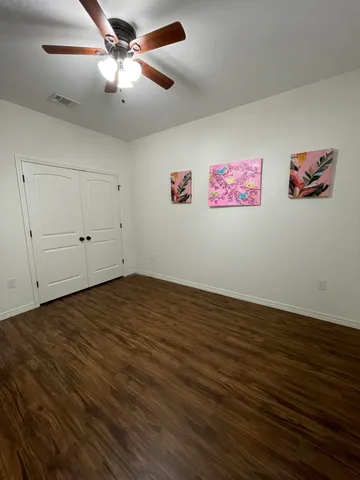 an empty room with wooden floor and cabinet