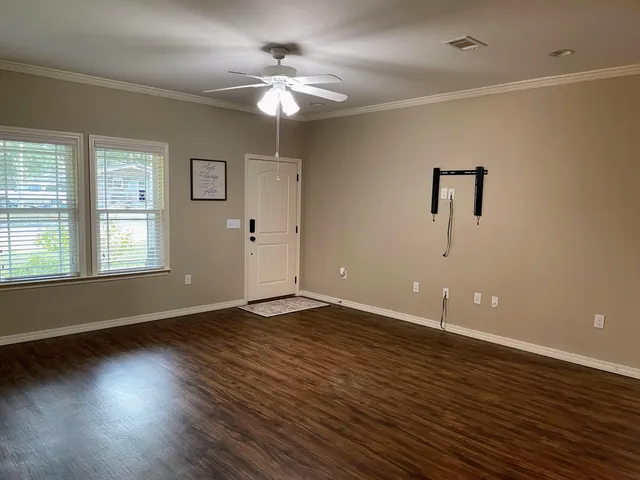 an empty room with wooden floor chandelier fan and windows