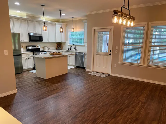 a kitchen with stainless steel appliances granite countertop a refrigerator a stove top oven a refrigerator and a wooden floors