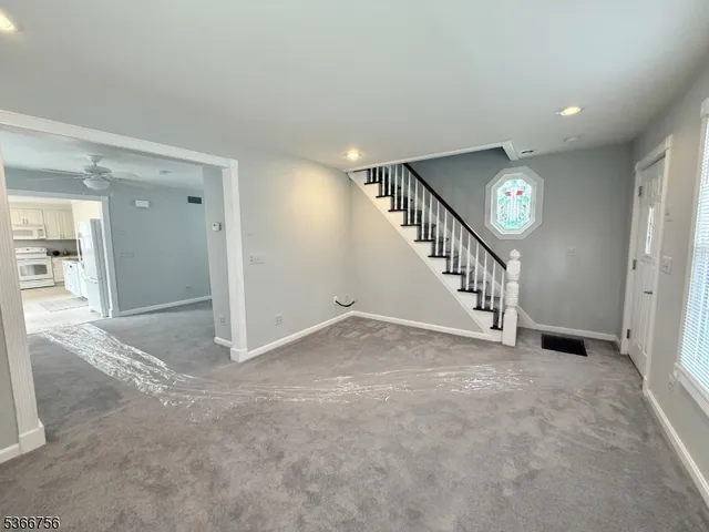 a view of an empty room with stairs and a view of bathroom