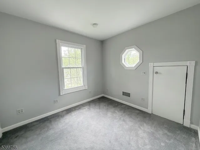 an empty room with a window and a fan