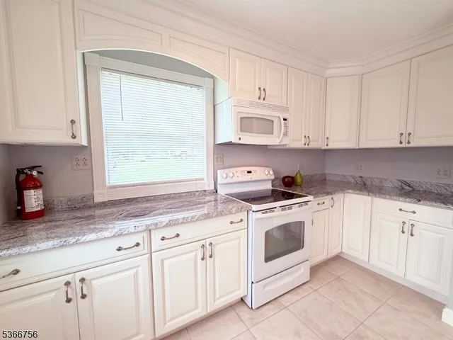 a kitchen with granite countertop white cabinets and white appliances