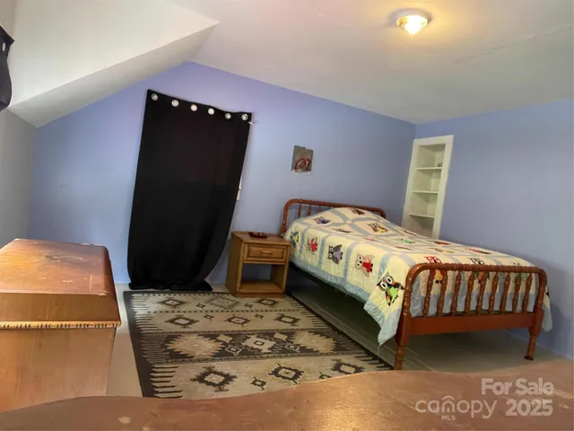 a view of a hallway with bed and wooden floor