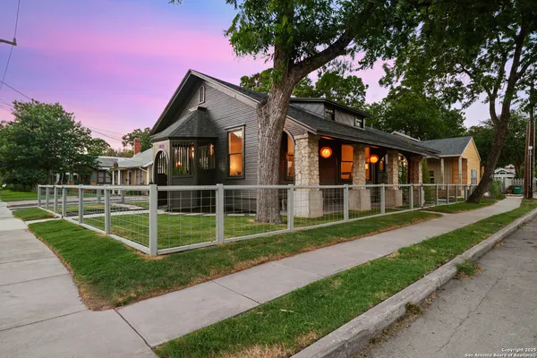 a view of a house with a yard and a large tree