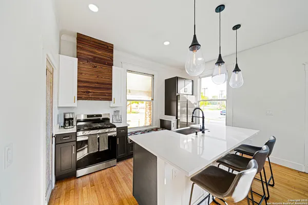 a kitchen with granite countertop a stove a sink a dining table and chairs