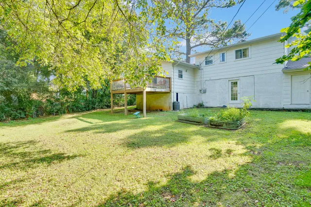 a view of a house with a yard and a large tree