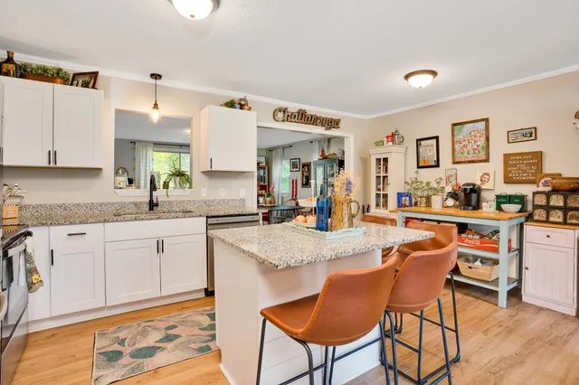 a kitchen with stainless steel appliances granite countertop a stove top oven a sink a dining table and chairs