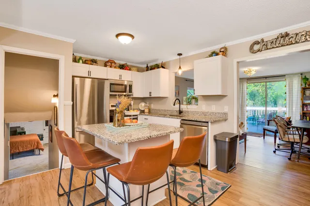 a kitchen with stainless steel appliances granite countertop a table chairs refrigerator and wooden cabinets