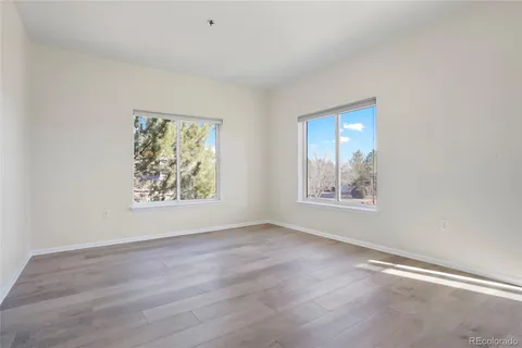 a view of an empty room with window and wooden floor