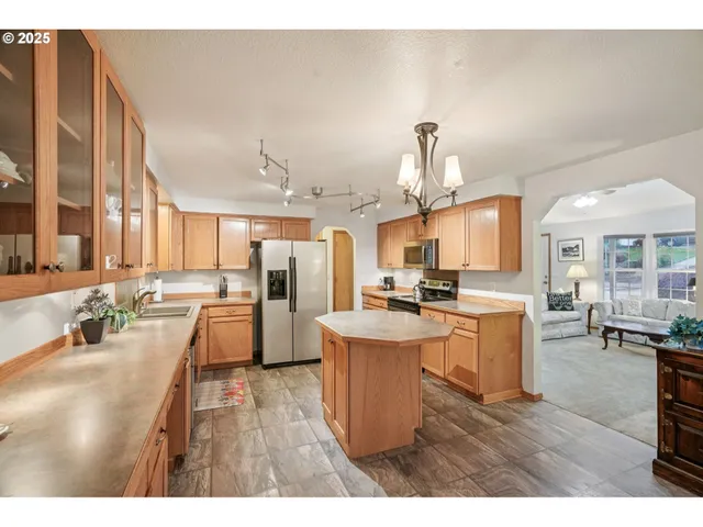 a kitchen with stainless steel appliances kitchen island granite countertop a stove a sink dishwasher and white cabinets with wooden floor