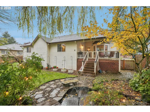 a view of a backyard with plants and large tree