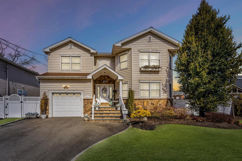 Traditional-style house featuring fence, an attached garage, stone siding, aphalt driveway, and a gate