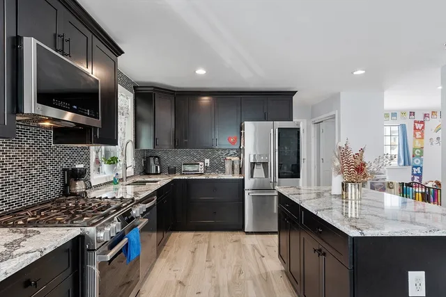 a kitchen with stainless steel appliances granite countertop a sink stove and refrigerator