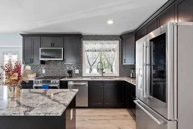a kitchen with stainless steel appliances granite countertop a sink stove and refrigerator