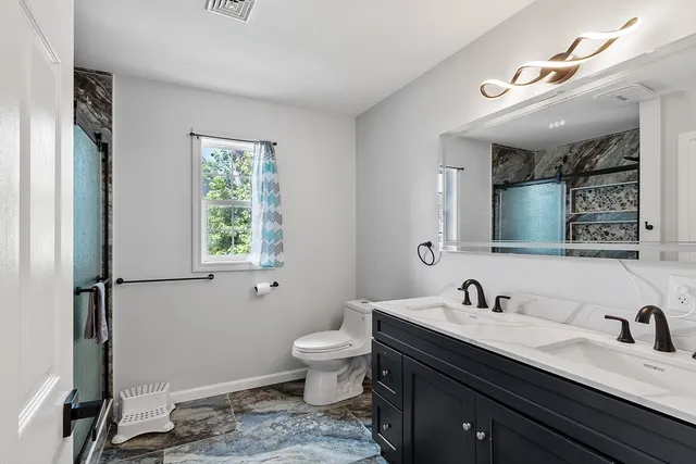 a bathroom with a granite countertop sink a toilet and a mirror