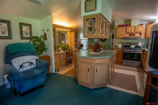 a living room with furniture a flat screen tv and kitchen view