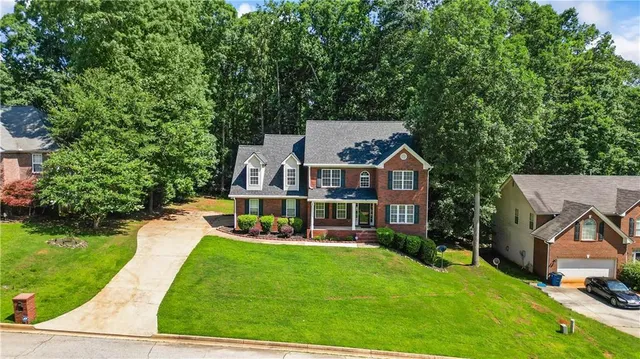 a view of a house with a big yard plants and large trees