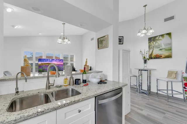 a kitchen with a sink dishwasher a dining table and chairs with wooden floor