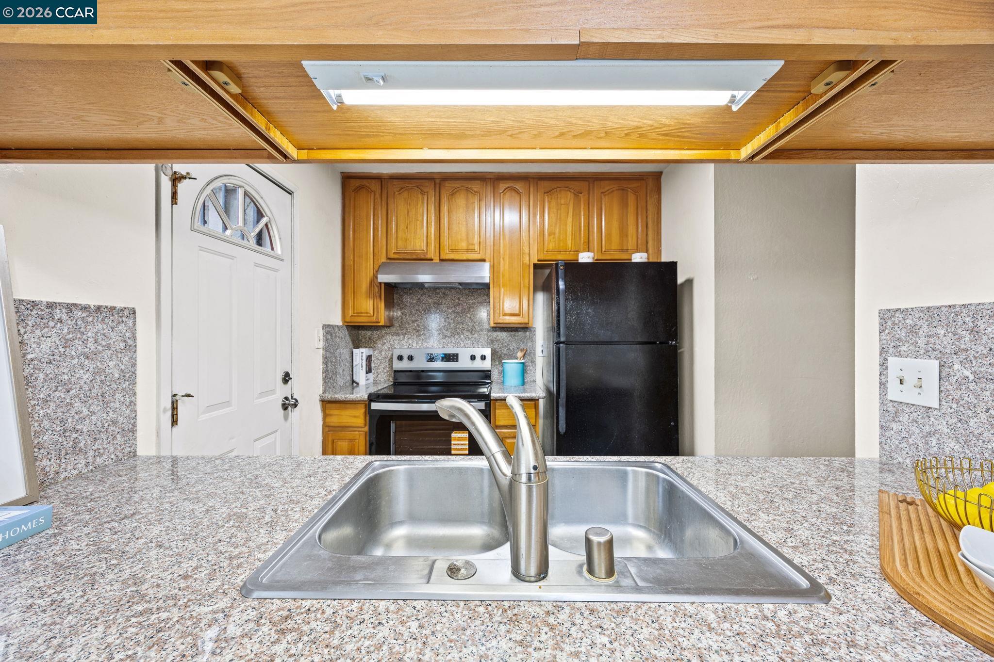 2069 Olivera Road, Unit E Concord, CA 94520 - Photo 6 of 18 a kitchen with a refrigerator a stove and a sink with wooden floor