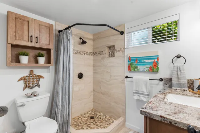 a bathroom with a granite countertop sink toilet and shower