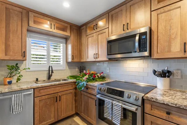 a kitchen with stainless steel appliances granite countertop a stove a microwave a sink and cabinets