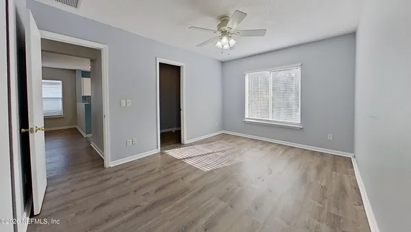 an empty room with wooden floor and windows