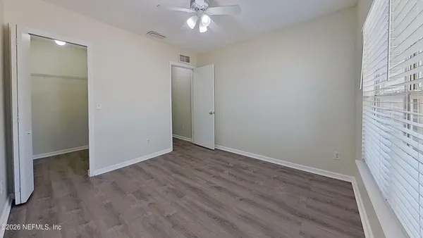 an empty room with wooden floor and fan