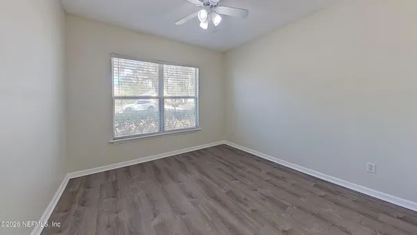 an empty room with wooden floor and windows