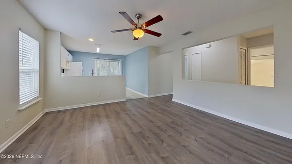 an empty room with wooden floor and windows