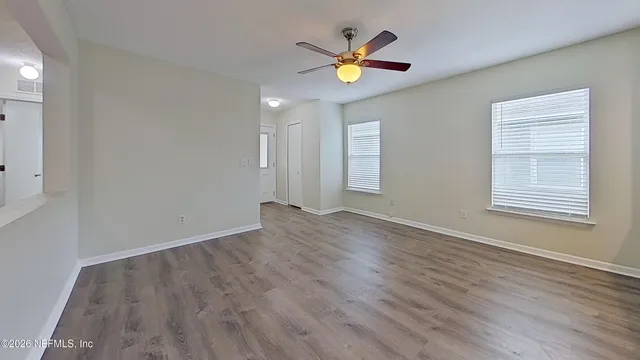 an empty room with wooden floor and windows