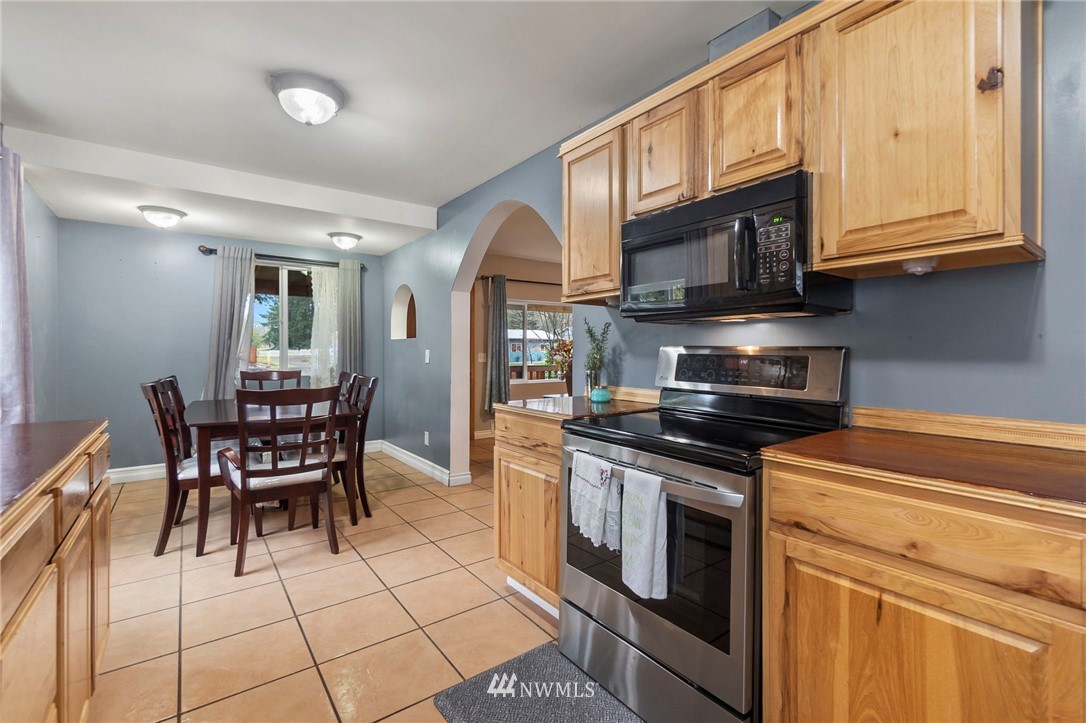 18349 Albany Street Southwest Rochester, WA 98579 - Photo 10 of 21 a kitchen with stainless steel appliances granite countertop a stove top oven a dining table and chairs with wooden floor