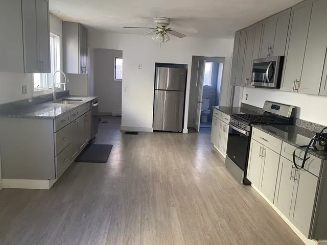 a large kitchen with a center island wooden floor stainless steel appliances and cabinets