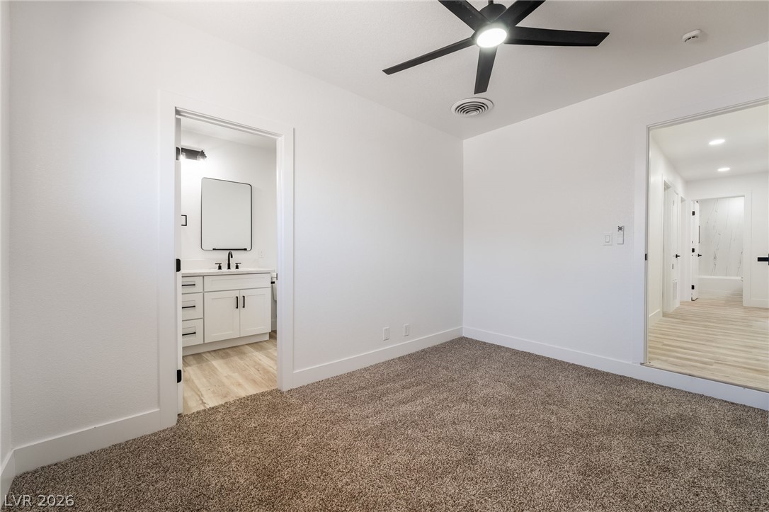 39 Lowery Street Henderson, NV 89015 - Photo 14 of 40 A well-lit bedroom offering plush carpet and direct access to a private bathroom.