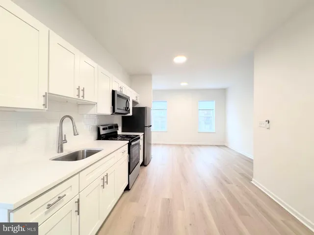 a kitchen with granite countertop a sink dishwasher a stove and a refrigerator with wooden floor