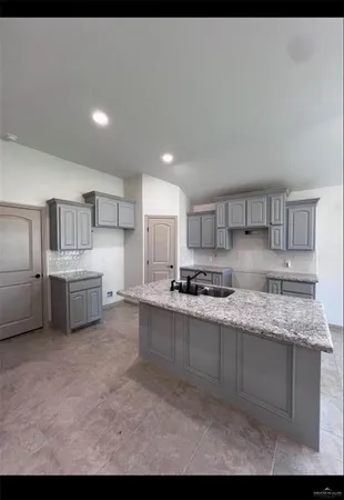 a large white kitchen with stainless steel appliances granite countertop a stove a sink a refrigerator and white cabinets