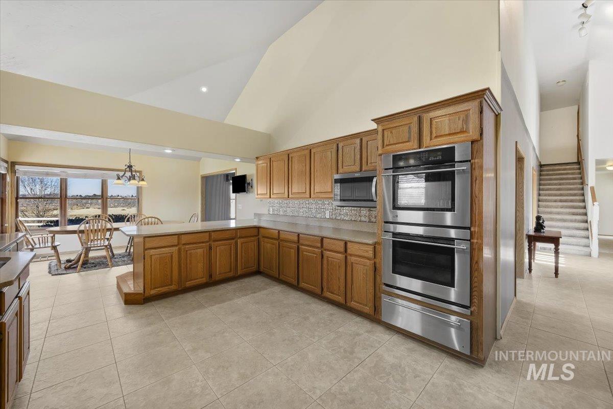 474 Kay Drive Twin Falls, ID 83301 - Photo 12 of 38 Kitchen with stainless steel appliances, a peninsula, lofted ceiling, a warming drawer, and wood finish cabinets