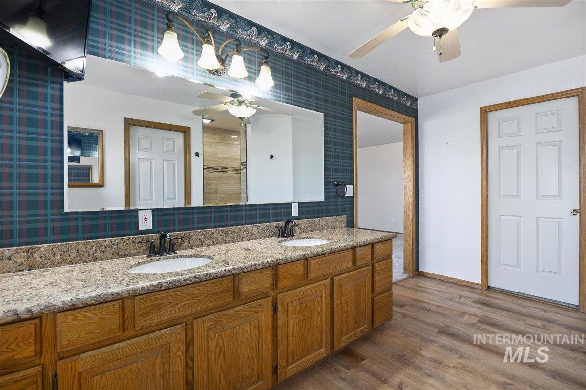 474 Kay Drive Twin Falls, ID 83301 - Photo 17 of 38 Full bath featuring wallpapered walls, double vanity, dark wood-type flooring, a ceiling fan, and tiled shower