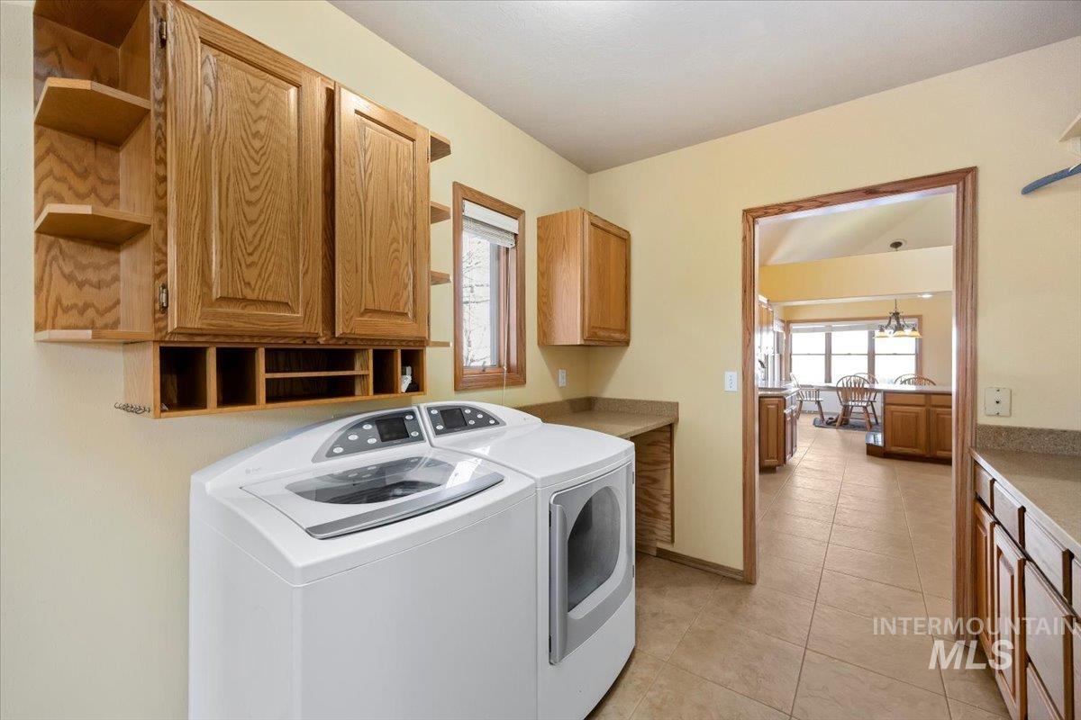 474 Kay Drive Twin Falls, ID 83301 - Photo 27 of 38 Laundry room with washing machine and clothes dryer, light tile patterned floors, and cabinet space