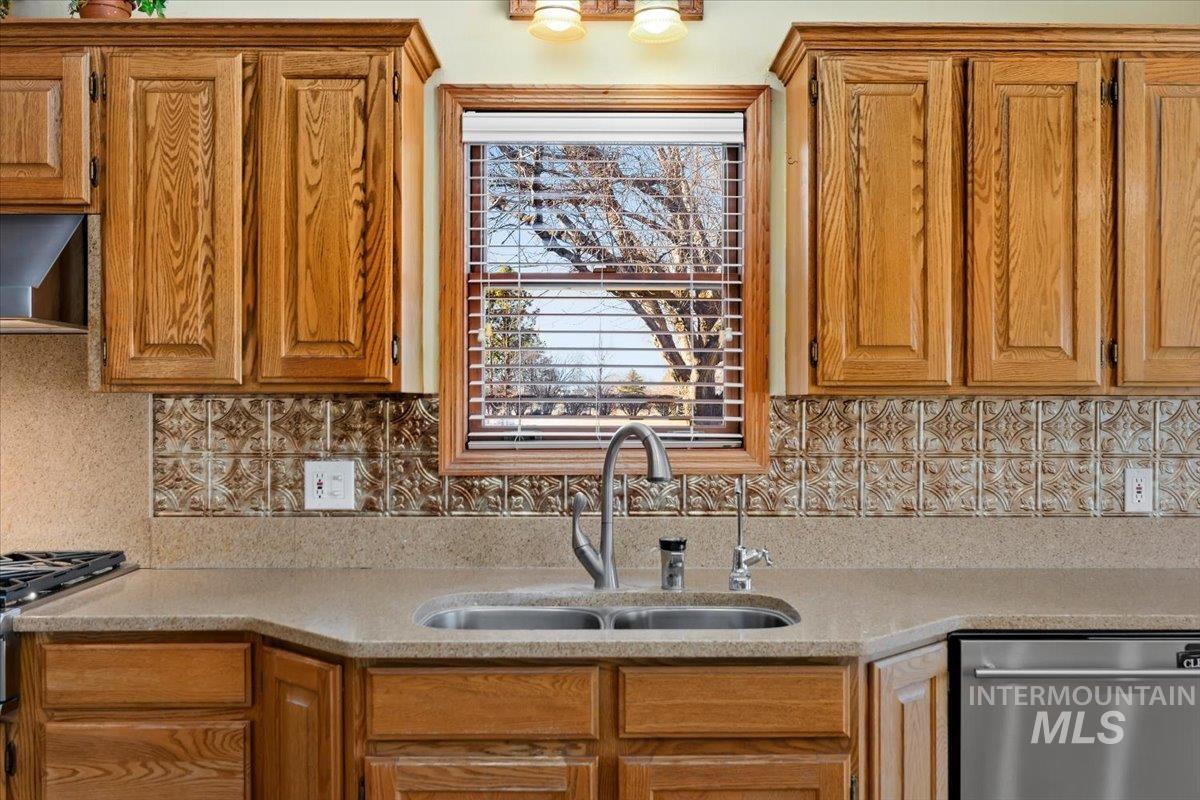474 Kay Drive Twin Falls, ID 83301 - Photo 10 of 38 Kitchen featuring stainless steel appliances, wood finish cabinetry, light stone counters, exhaust hood, and tasteful backsplash