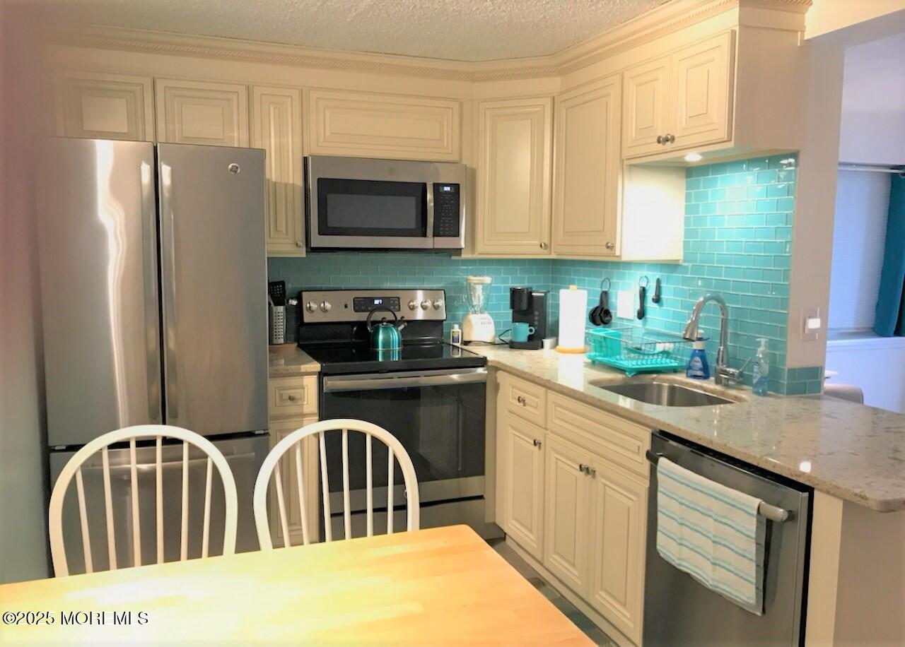 1 2nd Avenue, Unit 3 Seaside Heights, NJ 08751 - Photo 4 of 14 a kitchen with stainless steel appliances granite countertop a refrigerator a stove a sink dishwasher and white cabinets with wooden floor