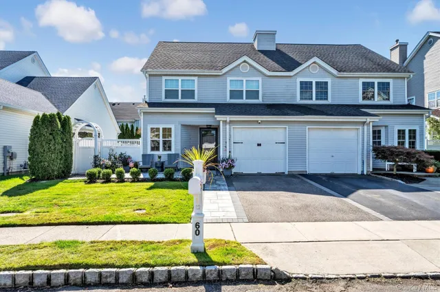 a view of a white house with a big yard and potted plants
