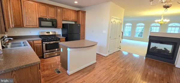 a kitchen with a refrigerator stove and wooden floor